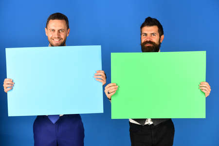 Men with beards hold boards on blue background.