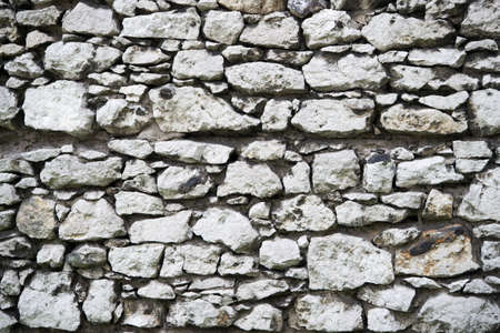Old stony wall in Krakow texture background. Ancient background empty wall made out of stones in Krakow. Old building material concept. Ancient stony fortification or part of defensesの写真素材