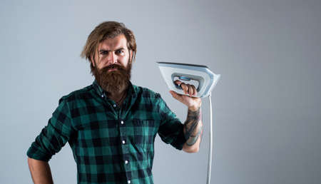 Maid for you. Man Ironing Clothes. man concentrated on ironing a shirt. laundry room at home. Clothes ironing board household concept. domestic everyday duty. man ironing at homeの写真素材