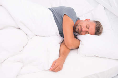 Sexy man lying on bed with soft pillows at home. Perfect morning. Tips sleeping better. male health. Enjoying time at home. Relaxing in bedroom. day dreaming male. Day sleeping. Morning of a new dayの写真素材