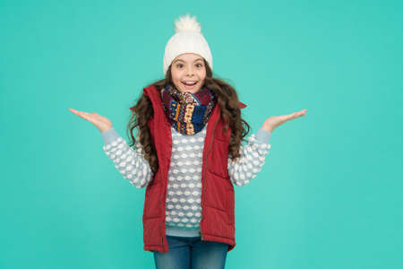 happy surprised teen girl wear warm clothes. winter kid fashion. child with long curly hair in knitted hat. cold season style christmas activity. childhood happiness. thermal clothing. copy spaceの写真素材