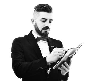 Bearded businessman with moustache and smile holds organizer and writesの写真素材