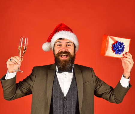 Man in smart suit and Santa hat on red background.