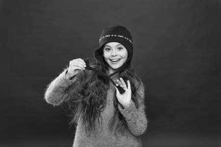 Stay warm. Little girl winter fashion accessory. Small child long hair wear hat burgundy background. Cute model enjoy winter style. Its cold outside. Winter outfit. Little kid wear knitted hatの写真素材