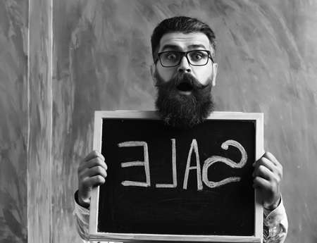 Bearded man, brutal caucasian hipster holding sale inscription on blackboardの写真素材