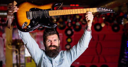 Rock musician concept. Musician with beard raise up electric guitar