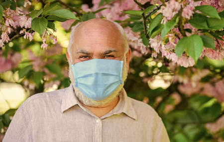 Impossible scent. wear mask in blossoming pink sakura park. care your health. man in protective...