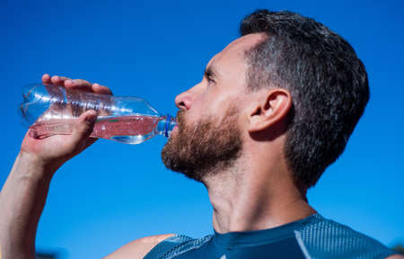 bearded man drinking water because of thirst after training, sport and hydration