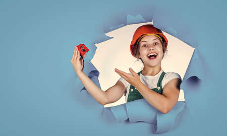 happy childhood. self-retracting metal tape measure. Little girl using a measuring tape. construction worker with tape measure. Cute kid as a construction worker. kid repairing home. copy spaceの写真素材