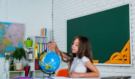 where to go. back to school. teen girl work in classroom near blackboard. cheerful kid learning geography. modern education. knowledge day. child pupil use globe. girl is college studentの写真素材