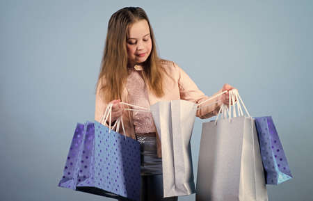 In shopping store. Kid fashion. shop assistant with package. Sales and discounts. Happy child. Little girl with gifts. Small girl with shopping bags. Holiday purchase saving. shopping storeの写真素材
