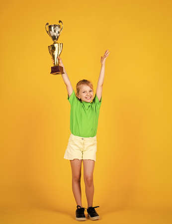 Great progress. Victory and win. Deserved award. Sport achievement. sport success concept. happy childrens day. happy childhood. small girl hold golden reward of championship cup. she is championの写真素材