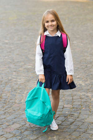 Happy little kid smile in fashion uniform holding backpack outdoors, back to schoolの写真素材