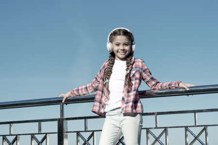 Girl child listen music outdoors with modern headphones. Enjoy music everywhere. Best music apps...