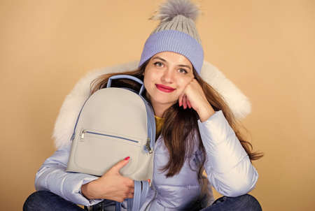 Fashion accessory. Little backpack and knitted hat. Total pastel outfit. Backpack is all you need. Girl adorable model showing her fancy leather backpack. Tender combination. Matching accessoriesの写真素材