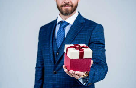 Having outside that looks as good as inside. Wrapped box in male hand. Box tied with ribbon. Gift shop. Present delivery. Boxing day. Holiday celebration. Businessman cropped viewの写真素材