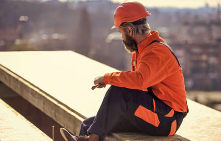 Install partially overlapping layers of material over roof insulation surfaces. Master repair roof. Flat roof installation. Roofer constructing roof. Man roofing surface. Materials requirementsの写真素材