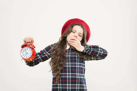 Its time to go to sleep. Sleepy little girl in evening time on yellow background. Yawning small child holding alarm clock. Late time. Break time, refresh yourselfの写真素材
