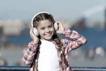 Adorable music lover. Little kid enjoy listening to music. Little girl wearing stereo headphones. Little child with wireless headset. Little child using technology for leisure or music educationの写真素材