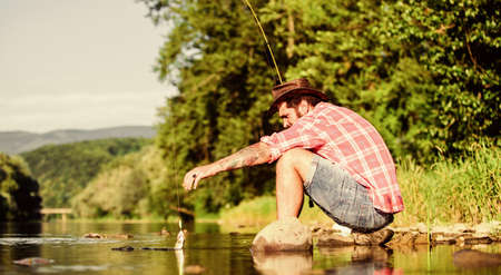 Gone Fishing. successful fisherman in lake water. hipster fishing with spoon-bait. big game fishing. relax on nature. fly fish hobby. Summer activity. mature bearded man with fish on rodの写真素材