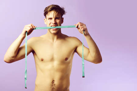 Young sportsman with cyan measuring tape on light purple backgroundの写真素材