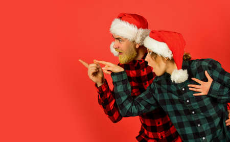 Family shopping. Christmas party. Idea for fun. Good mood. Winter joy. Couple in love pointing copy space. Look at this. Santa Claus style. Christmas time. Man and woman christmas holiday celebrationの写真素材