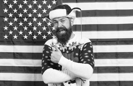 American customs. Brutal man wear knitted sweater. American tradition. Bearded hipster american flag background. Xmas new year. Spirit of patriotism. Christmas tradition from united states of Americaの写真素材