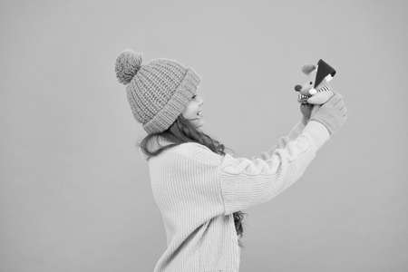 it is so cute. winter season joy. lets celebrate christmas. new year is here. xmas shopping and preparation. happy girl with christmas toy. small kid in warm clothes hold gift. happy holidayの写真素材