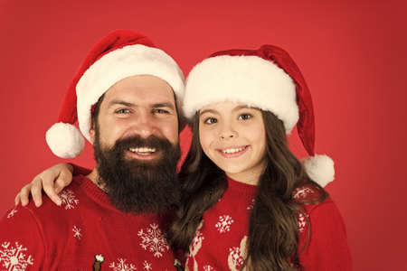 Best wishes. happy father and daughter love xmas. small girl and dad santa hat. daddy and kid red background. christmas time. new year party. happy to be together. winter holiday with familyの写真素材
