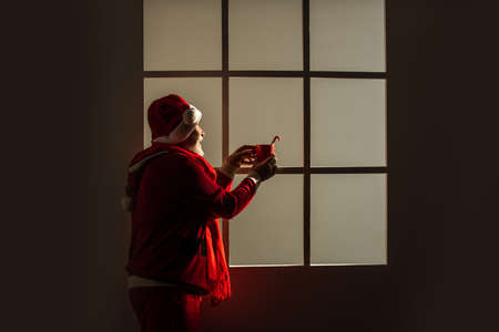 Ho Ho Ho. merry christmas. bearded santa in hat drink milk or cocoa. xmas presents and gift shopping time. winter holiday joy. funny senior man in santa claus costume. happy new 2021 yearの写真素材