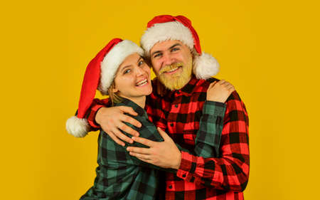 Santa team. Loving couple yellow background. Christmas magical time. We love christmas. Couple in love enjoy christmas holiday celebration. Family wear santa hats. Entertainment ideas for adultsの写真素材