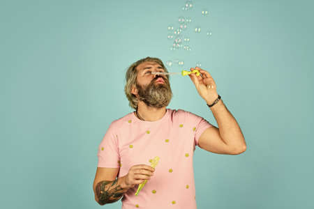 man with bubble blower. happy hipster in playful mood. Fall into childhood. feeling childish and childlike. real happiness. mature man blowing soap bubbles. stay carefree at any ageの写真素材