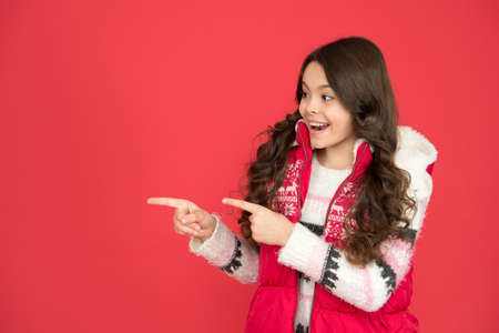 cheerful id pointing finger on copy space in warm winter clothing on new year holidays, winter shopping salesの写真素材
