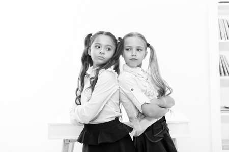 Schoolgirls standing back to back. Every day better. Little schoolgirls classmates friendly kids. Best friends relaxing. Schoolgirls tidy hairstyle relaxing having rest. Some kind of competitionの写真素材