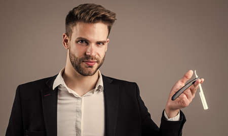 make new hairstyle. beauty and fashion. sexy man with barber tool for shaving. businessman or stylist. male hairdresser and barbershop. man hold razor blade for cutting hair. beard and hair careの写真素材