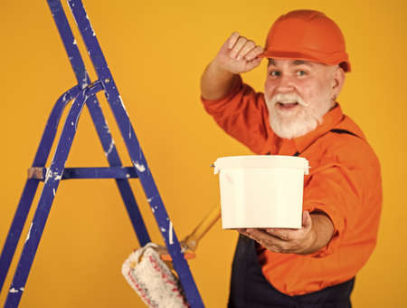 House Painting and Renovation Business. making repair tool. Painter working at construction site. senior man use roller on ladder. work in apartment. Craftsman With Paint Roller. selective focusの写真素材