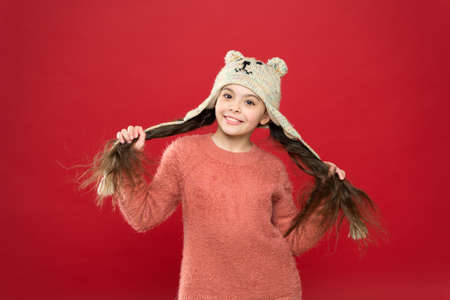 Happiness and joy. Winter outfit. Small child long hair wear hat red background. Cute model enjoy...