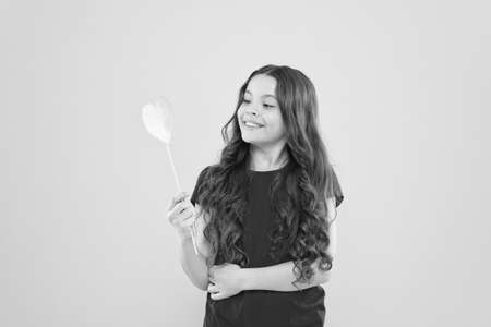 happy birthday to you. cheerful child with beautiful long hair. little beauty. birthday party time. smiling little girl party heart. party elements. happy childhood. small kid yellow backgroundの写真素材