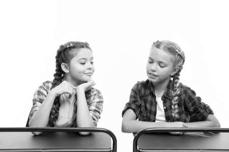 Cheating on the exam. Little schoolchildren passing exam isolated on white. Small girl peeping at her classmate during exam. Their first examの写真素材