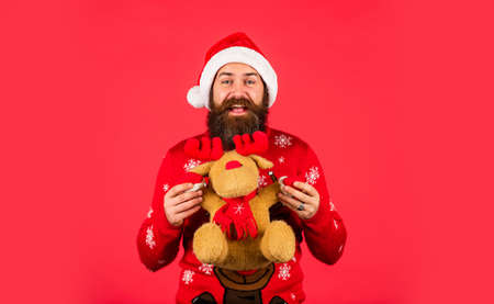 Plush deer. Hipster man hold Christmas gift. Happy man playful mood. Happy new year. Helping Santa Claus. Symbol of Christmas. Christmas eve. Gifts for kids. Dear Santa. Bearded man reindeer toyの写真素材