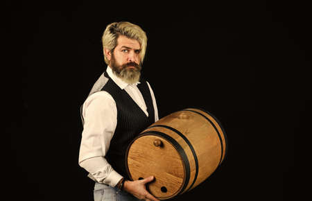 Winery concept. Advice on Buying Old and Rare wines. Natural wine. Producing wine family tradition. Man bearded hipster wooden barrel for wine black background. Homemade wine. Fermentation productの写真素材