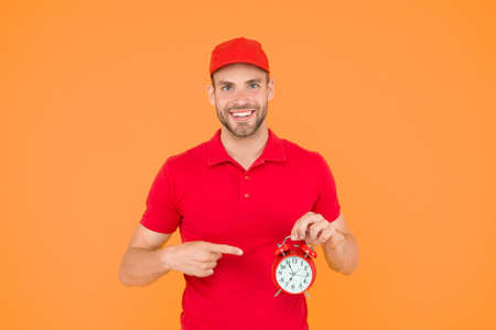 Always in time. Happy man with alarm clock on yellow background. Delivering your purchase. Courier service delivery. Salesman and courier career. Courier and delivery service. Postman delivery workerの写真素材