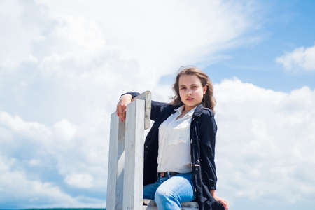 She is really cute. cute child on sky background. hairdresser salon. casual fashionable look. beautiful teen girl with curly hair. kid fashion style. female natural beauty. happy childhoodの写真素材