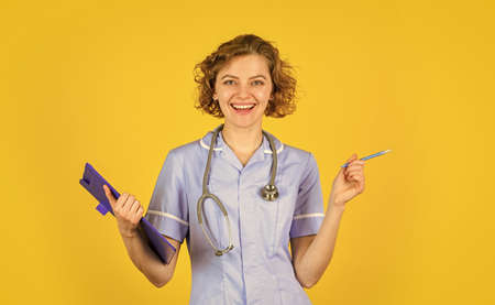 best treatment for you. nurse holding binder and wearing stethoscope. Smiling female doctor with a folder in uniform standing. Portrait of lovely nurse with a folder. She is wearing a stethoscopeの写真素材