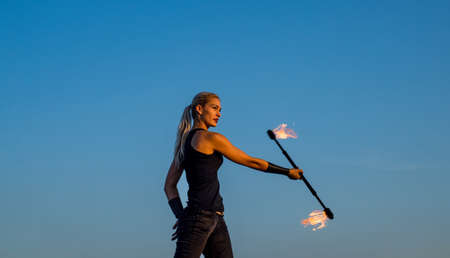 Sensual woman manipulate flaming rod. Fire performance. Baton twirling. Night party. Holiday...