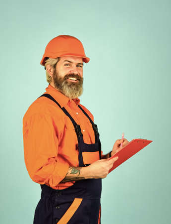 Checklist. Inspecting. Control concept. Foreman with document. Delivering building materials. Man in hard hat holding clipboard looking information. Buy materials for renovation. Bearded storekeeperの写真素材