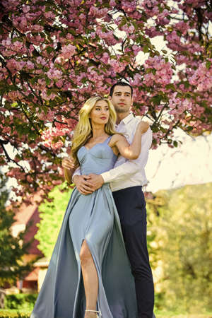 Loving people hug. Passion concept. Man and woman in blooming garden. Couple spend time in spring tree garden. Couple in love under sakura blossom. Couple in love under sakura blossom. Love storyの写真素材