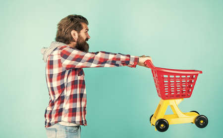 Sales assistant. empty toy trolley. really busy housekeeper. perfect husband. need shopping list. bearded man go shopping with toy empty shopping cart. customer pushing cart. buyer in supermarketの写真素材