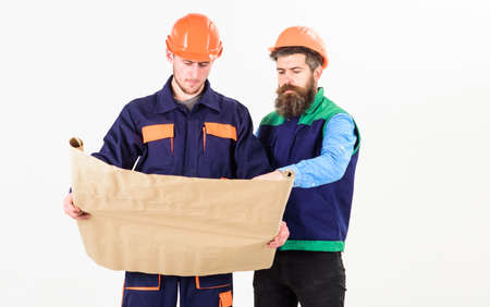 Architects in hard hat on busy faces looks at drawing
