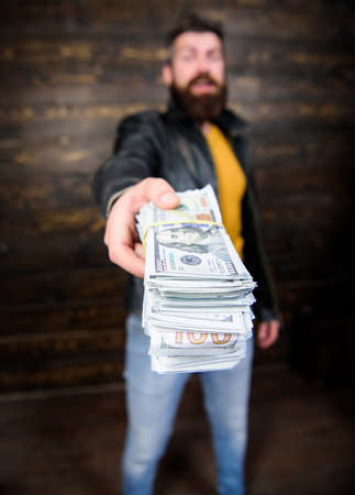 Man brutal bearded hipster wear leather jacket and hold cash money. Illegal profit and black cash. Guy mafia dealer with cash profit. Man give cash money bribe. Richness and wellbeing. Mafia businessの写真素材
